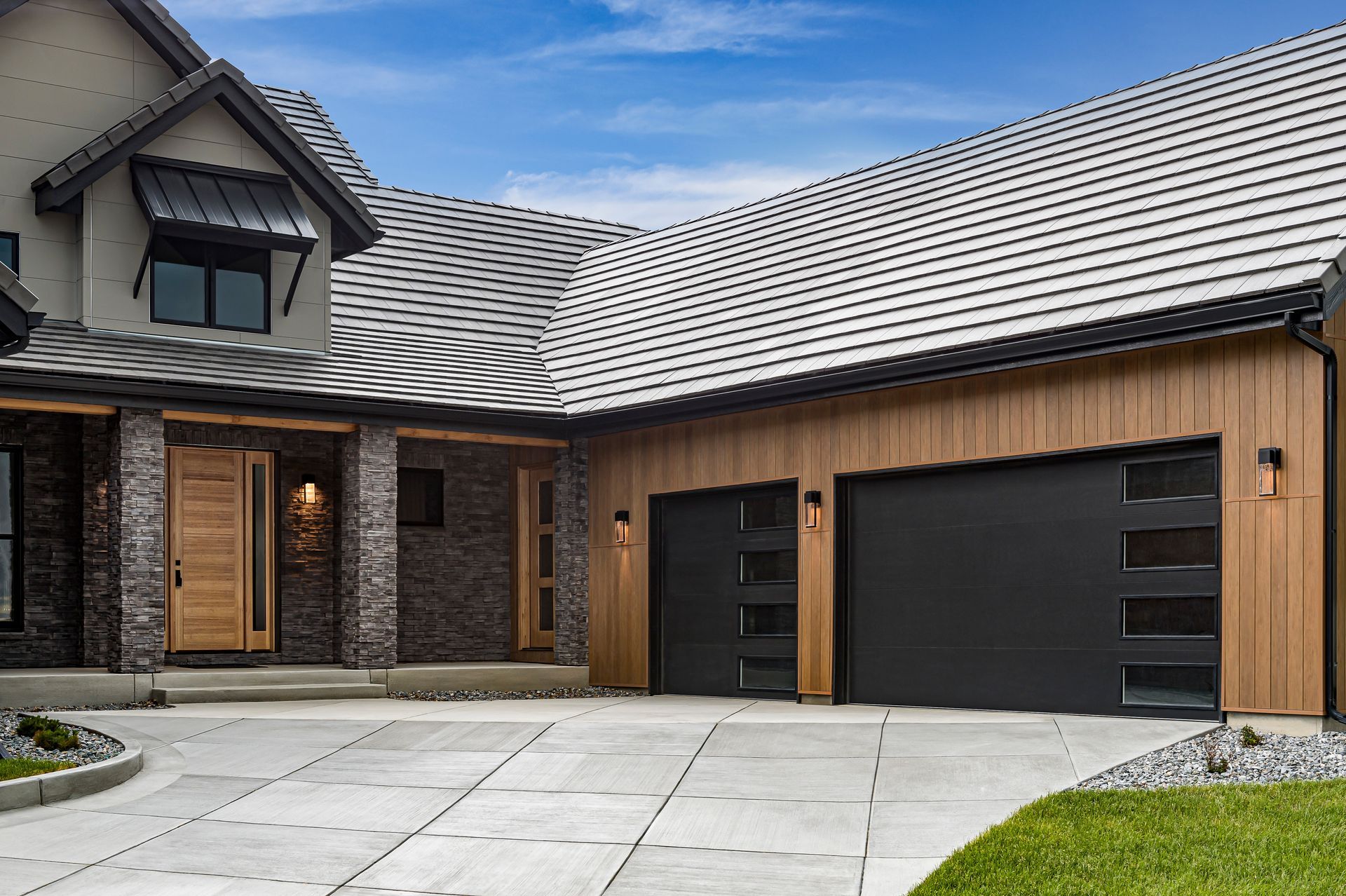 Modern house exterior with stone facade, wood accents, and two black garage doors