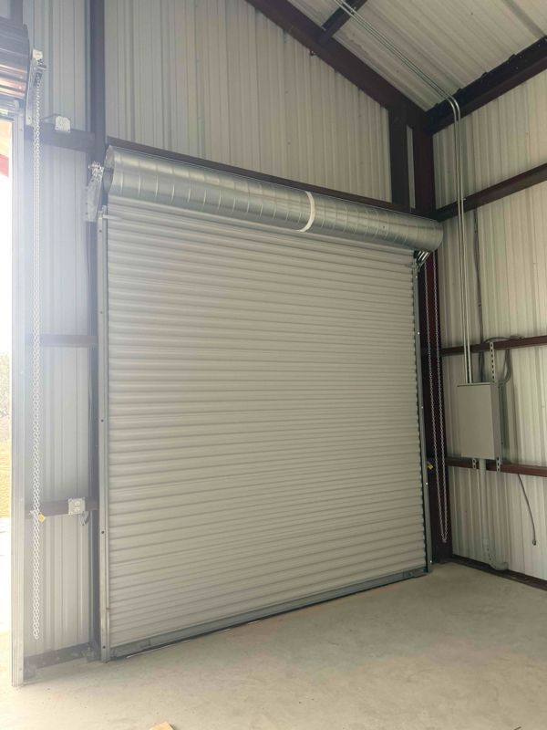 Closed gray roll-up garage door inside a metal industrial building