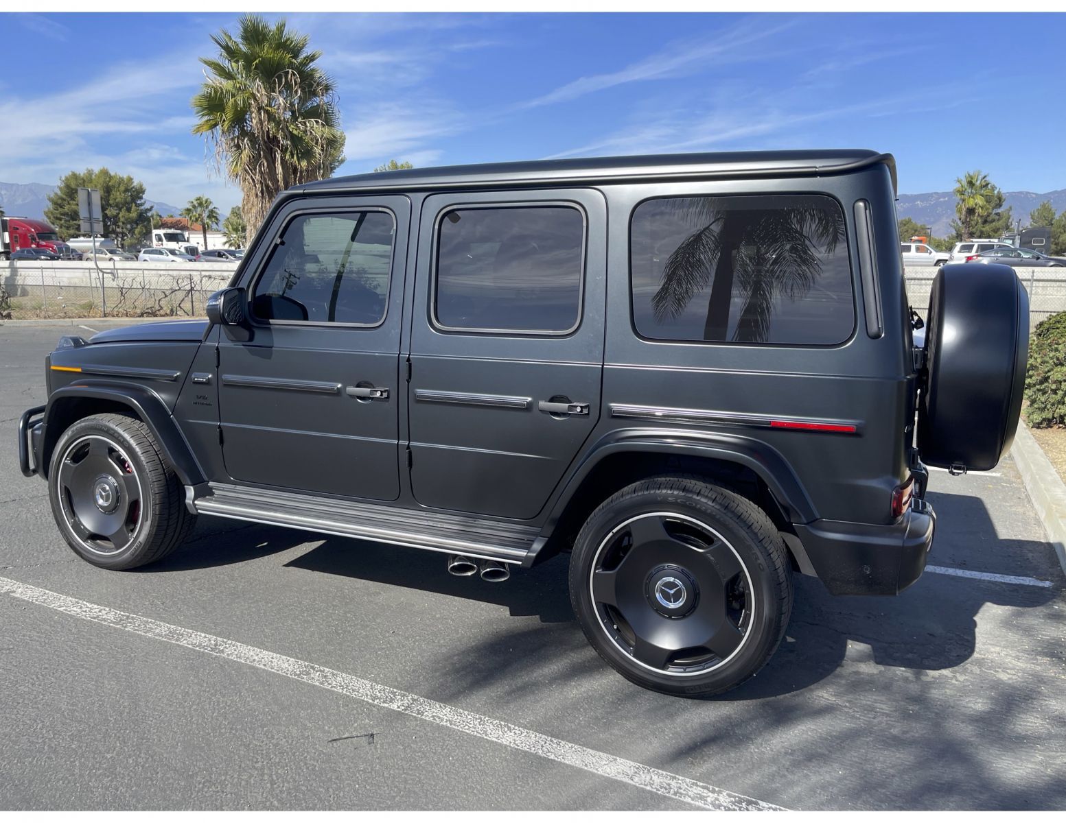 A black mercedes benz g63 amg is parked in a parking lot.