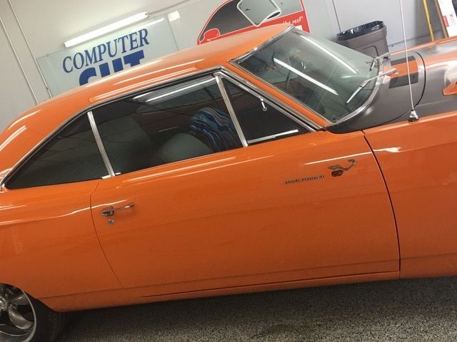 An orange car is parked in front of a sign that says computer cut.