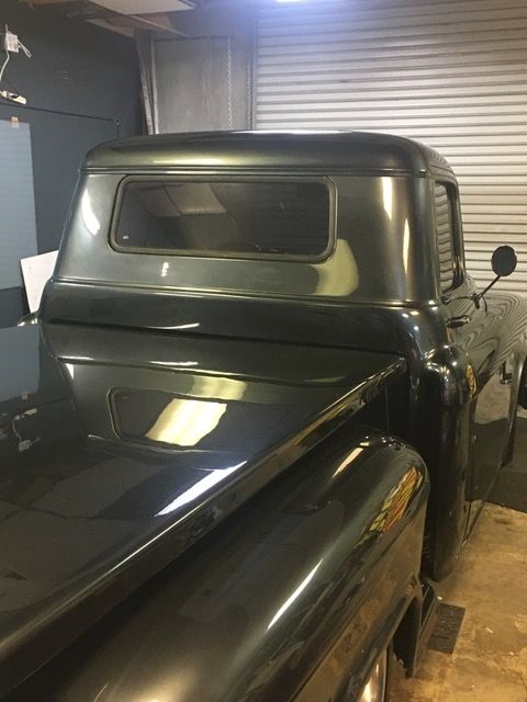 A black truck is parked in a garage next to a garage door.