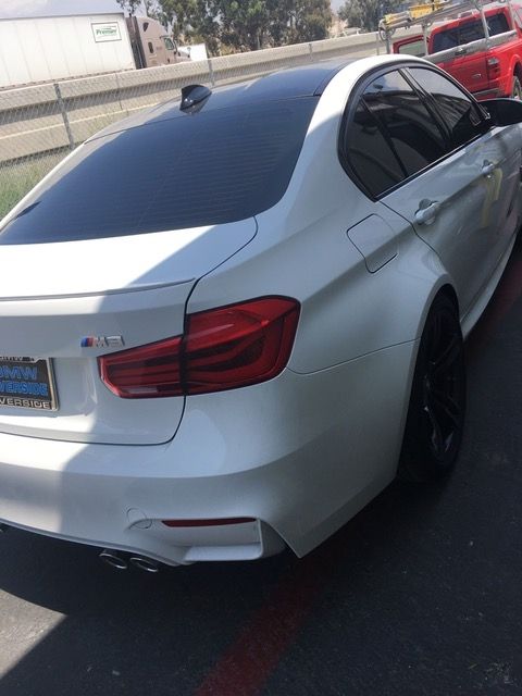 A white bmw is parked on the side of the road.