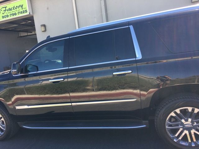 A black suv is parked in front of a factory.