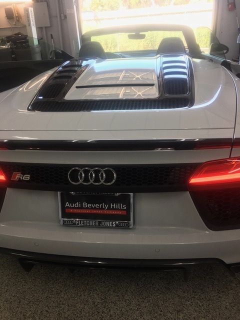 A white audi r8 spyder is parked in a garage.