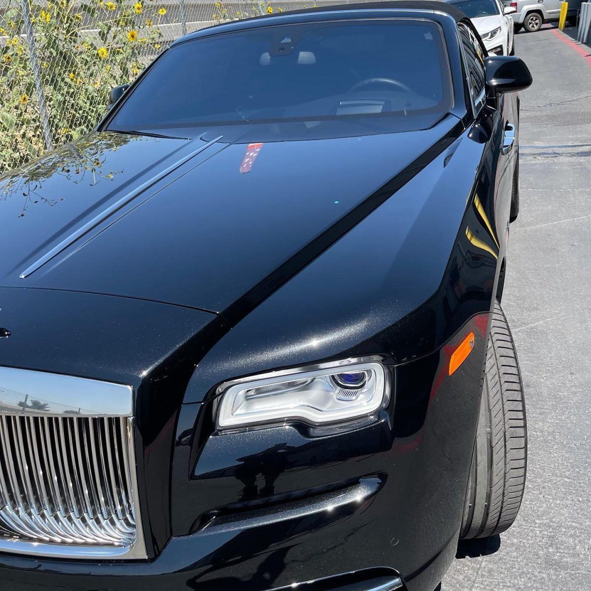 A black rolls royce is parked on the side of the road.