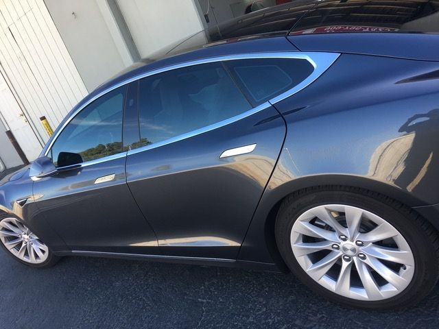A blue car is parked in front of a garage door.