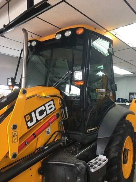 A yellow jcb tractor is parked in a garage.