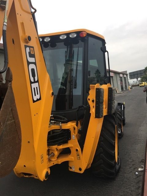 A yellow jcb tractor is parked on the side of the road.