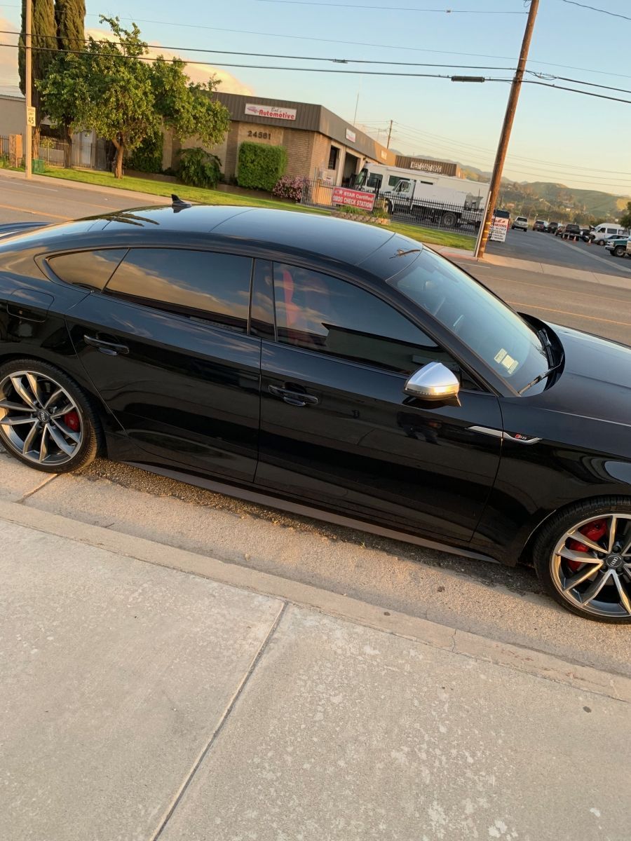 A black car is parked on the side of the road.