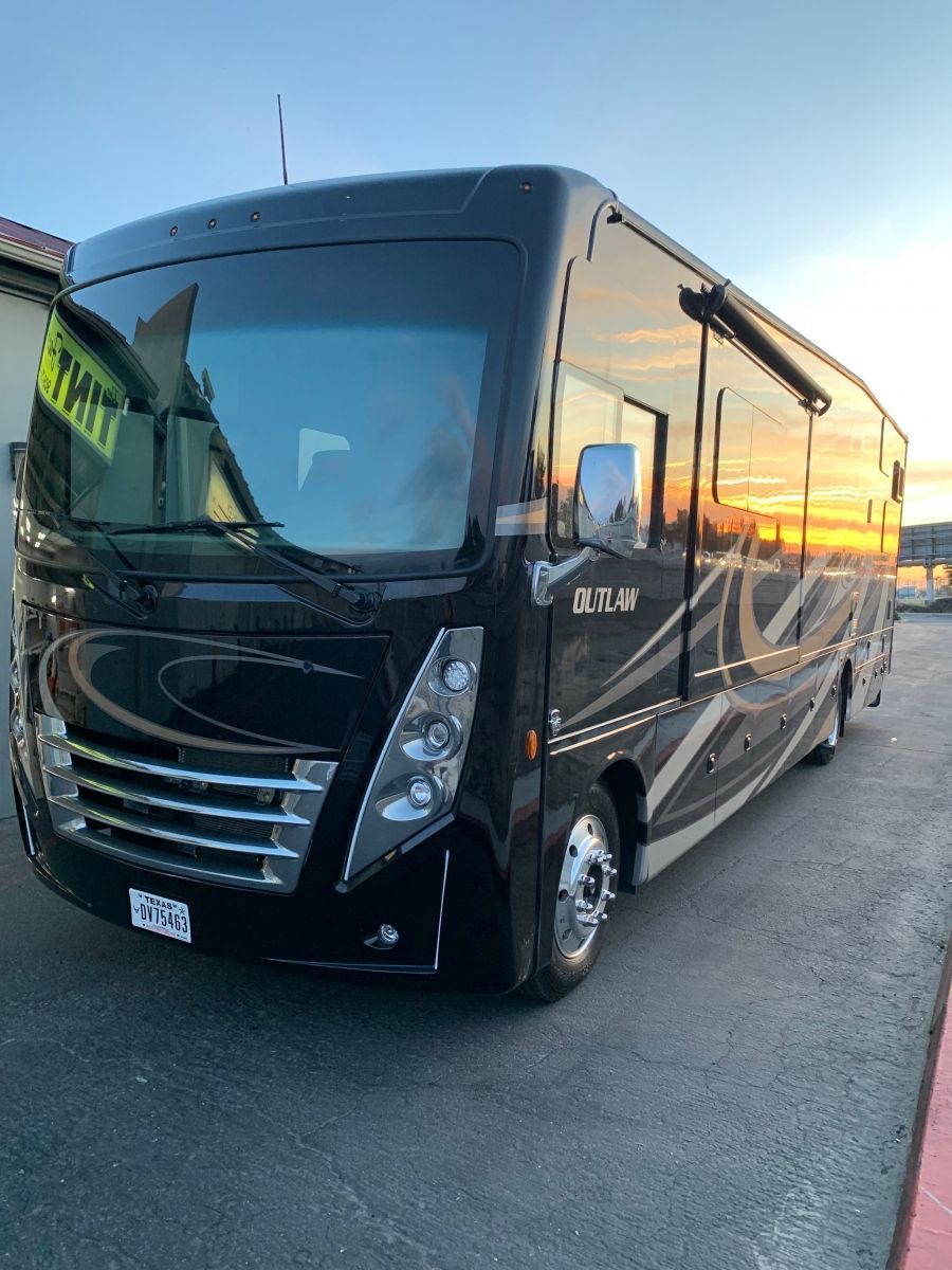 A large black rv is parked in a parking lot.