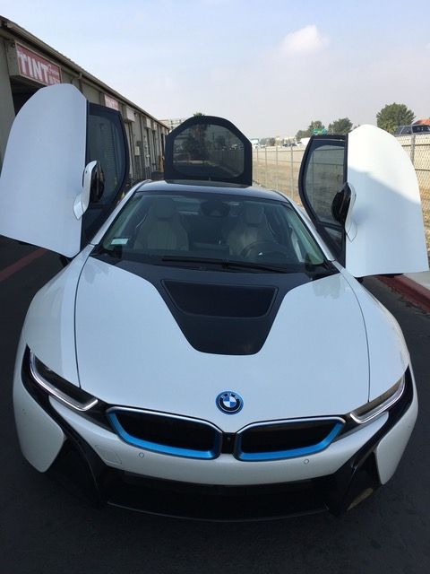 A white bmw is parked with its doors open.