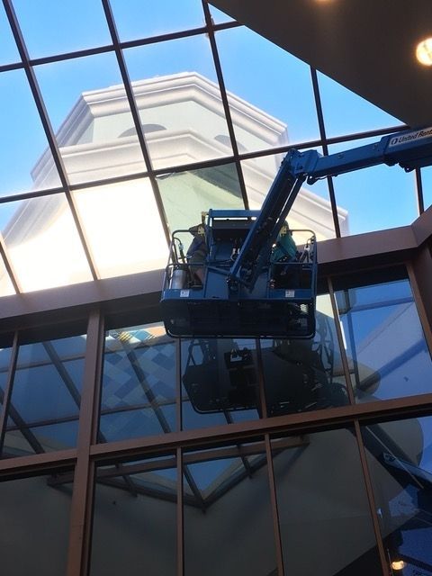 A blue crane is cleaning the windows of a building