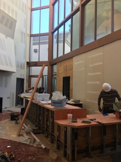 A man in a hard hat is standing in a room with a lot of windows