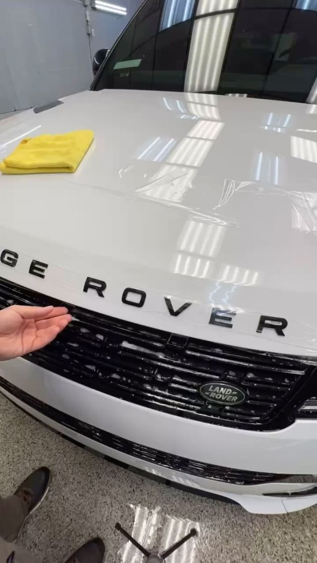 A person is holding the hood of a white range rover.