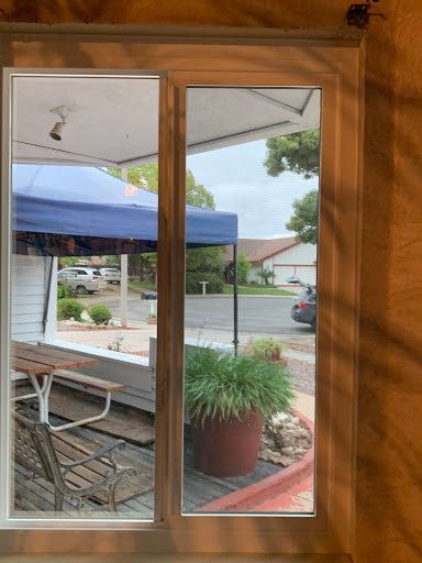A window with a view of a picnic table and a blue tent.