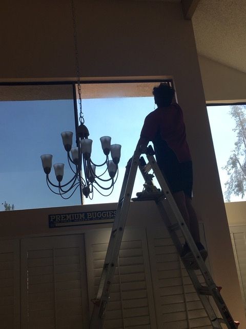 A man standing on a ladder cleaning a window