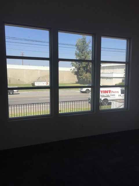 An empty room with three windows and a white van in the background.