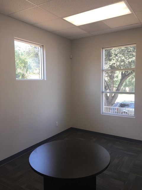 An empty room with a round table and two windows