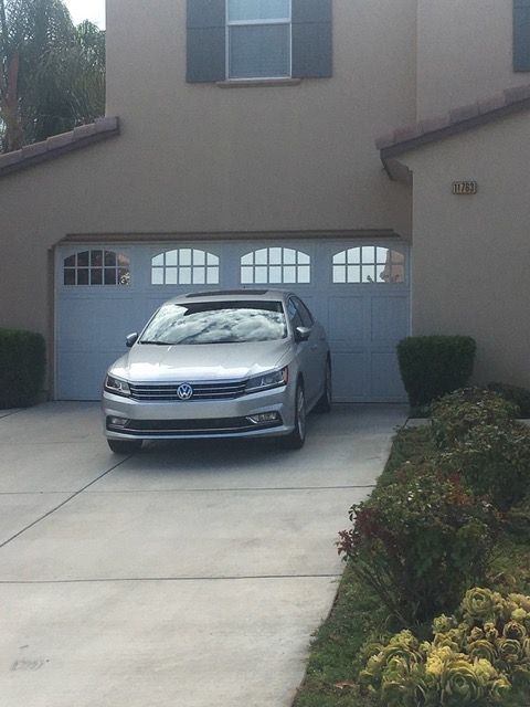 A silver car is parked in front of a house