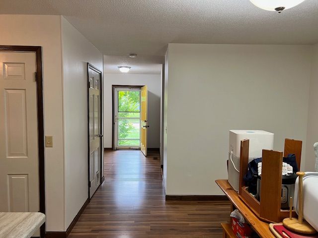Hallway with wooden floor, white walls, and a yellow door open to the outside.
