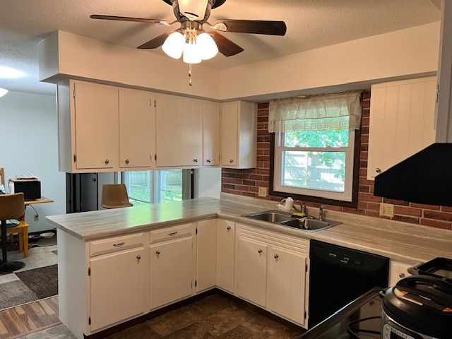White kitchen with cabinets, countertops, and appliances, including a black stove and dishwasher.