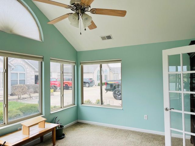 Sunroom with teal walls, windows, ceiling fan, and a bench.