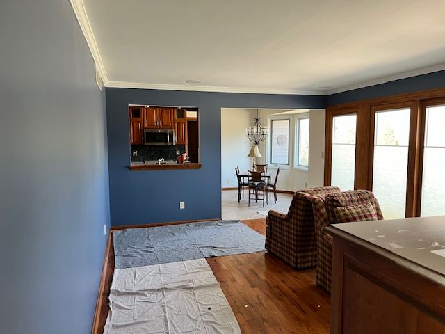 Blue painted living room with hardwood floors and open doorways to dining and kitchen areas.