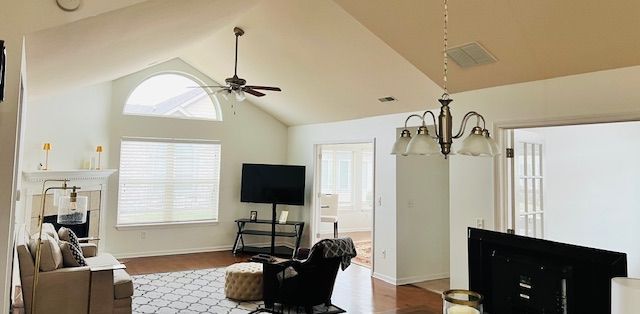 Living room with high ceiling, fireplace, TV, and chandelier.