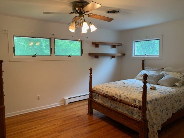 Bedroom with bed, windows, ceiling fan, and wooden shelves.