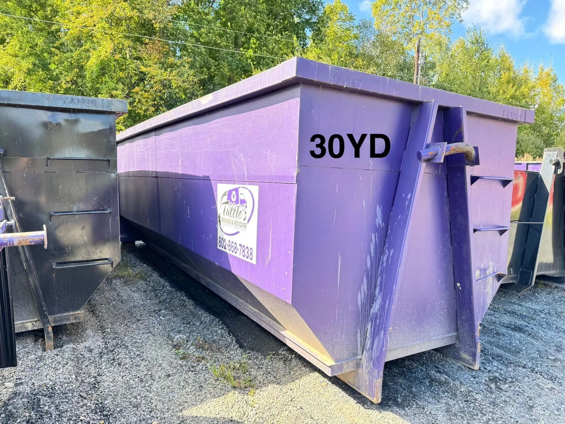 Purple 30-yard dumpster outdoors on gravel, with a logo and the words 