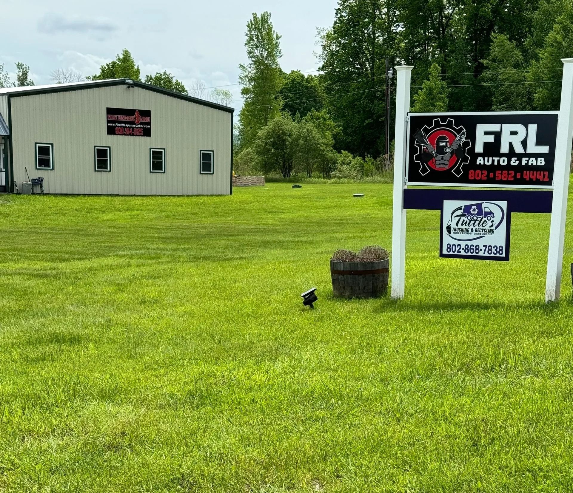 A building with signs for FRL Auto & Fab and another business, on a grassy lot.