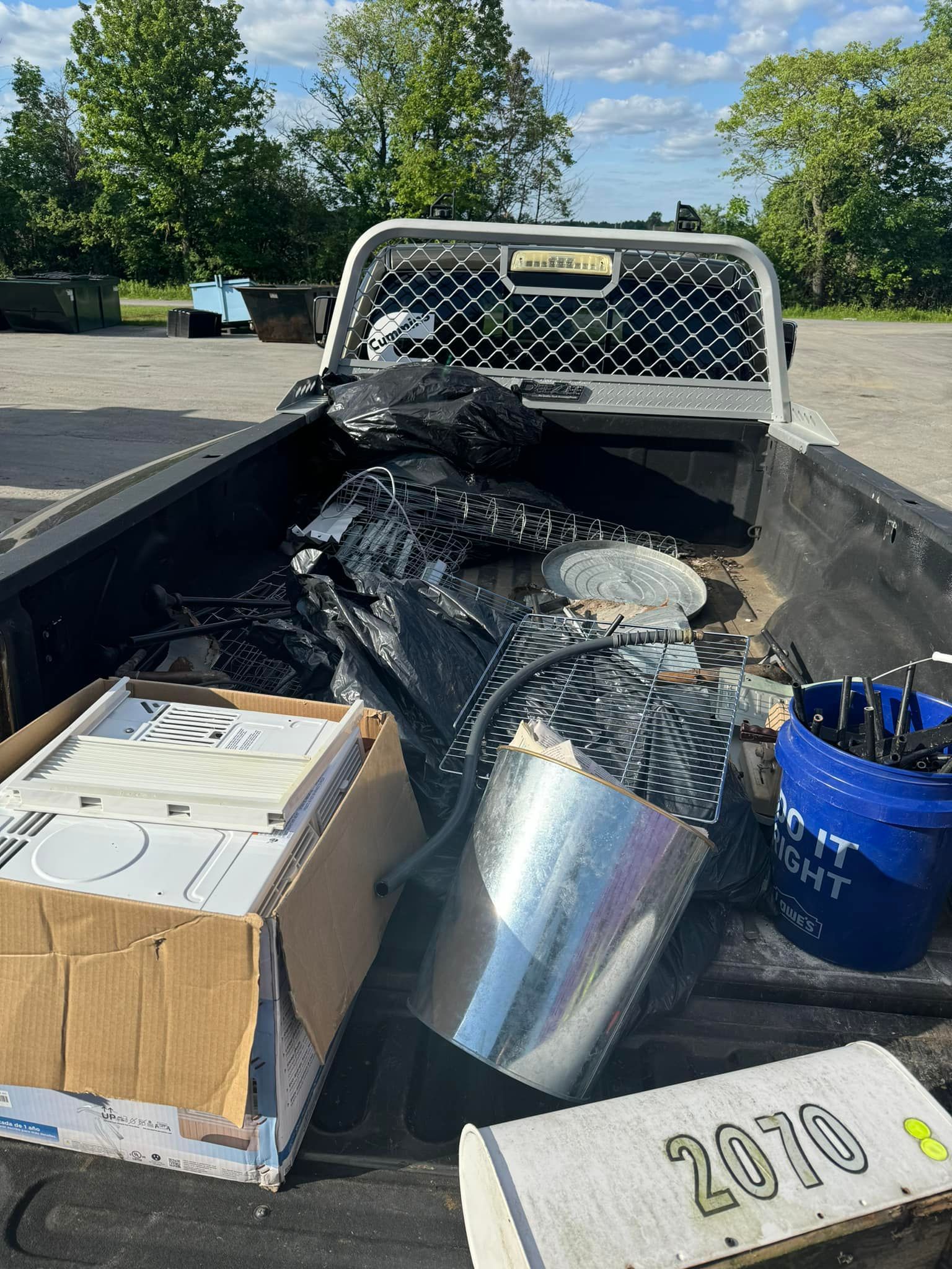 A truck bed loaded with junk. Contains a box, bucket, and various metal and black items.