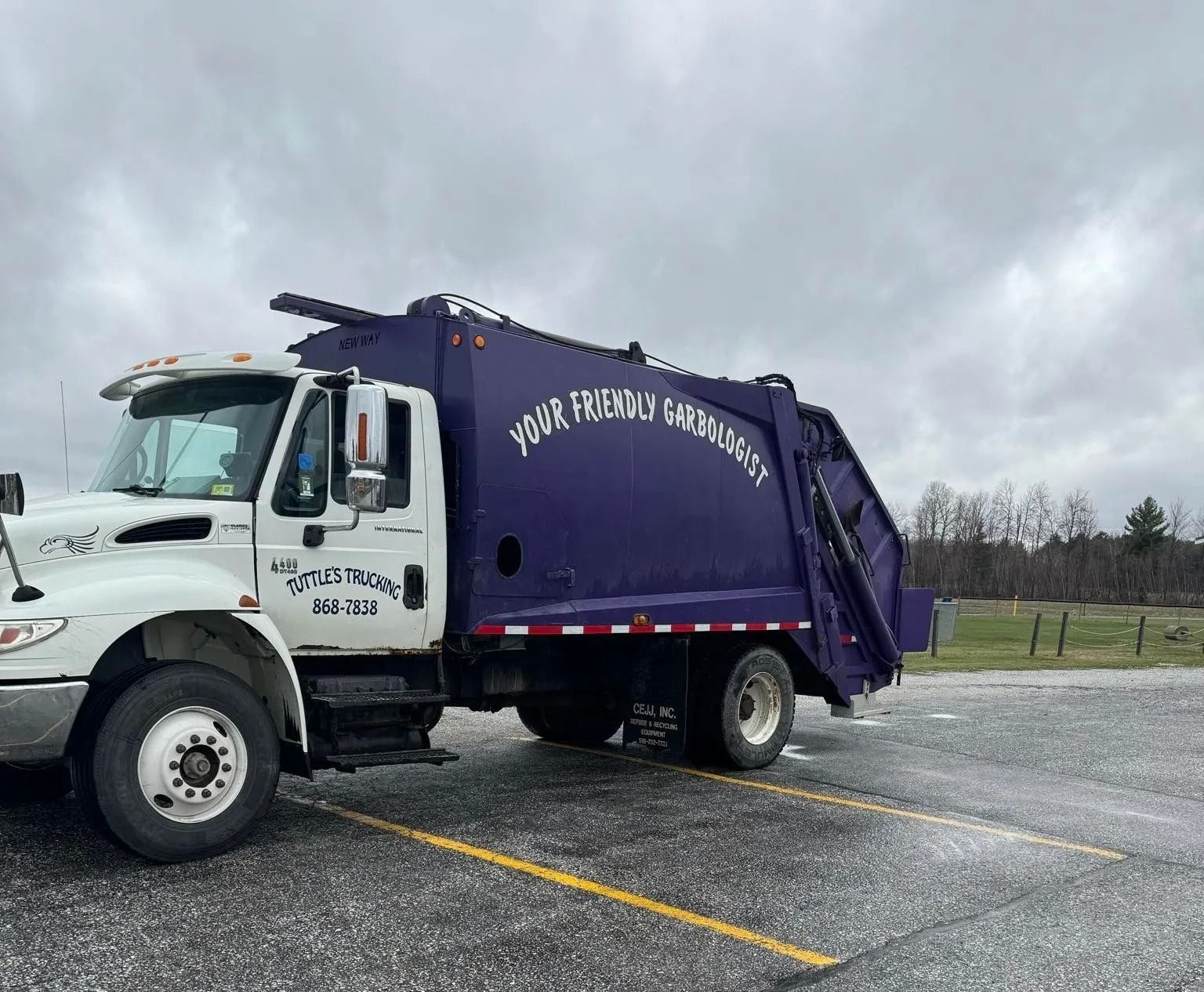 White garbage truck with purple container; 