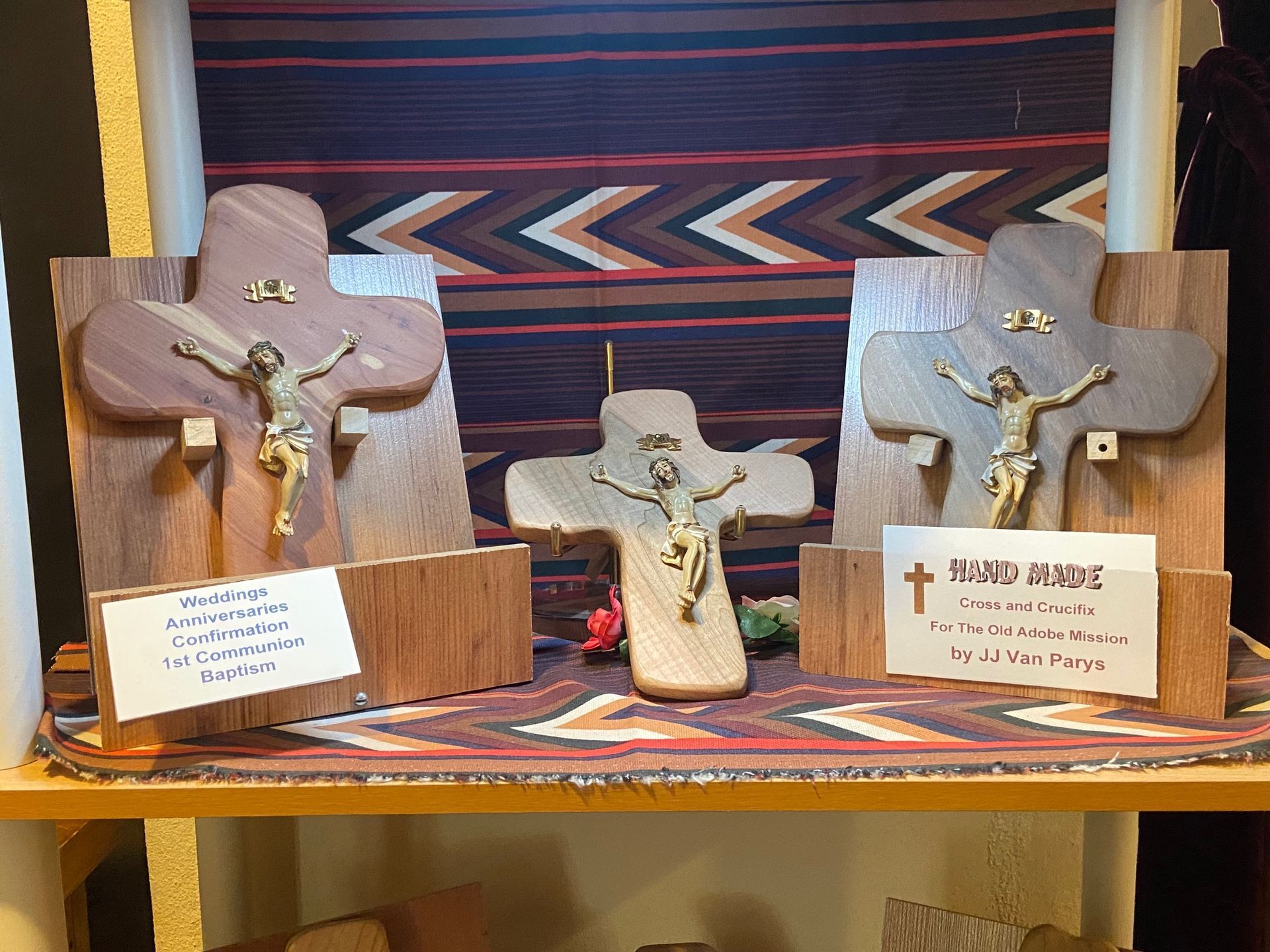 Three wooden crosses with jesus on them are on a shelf.