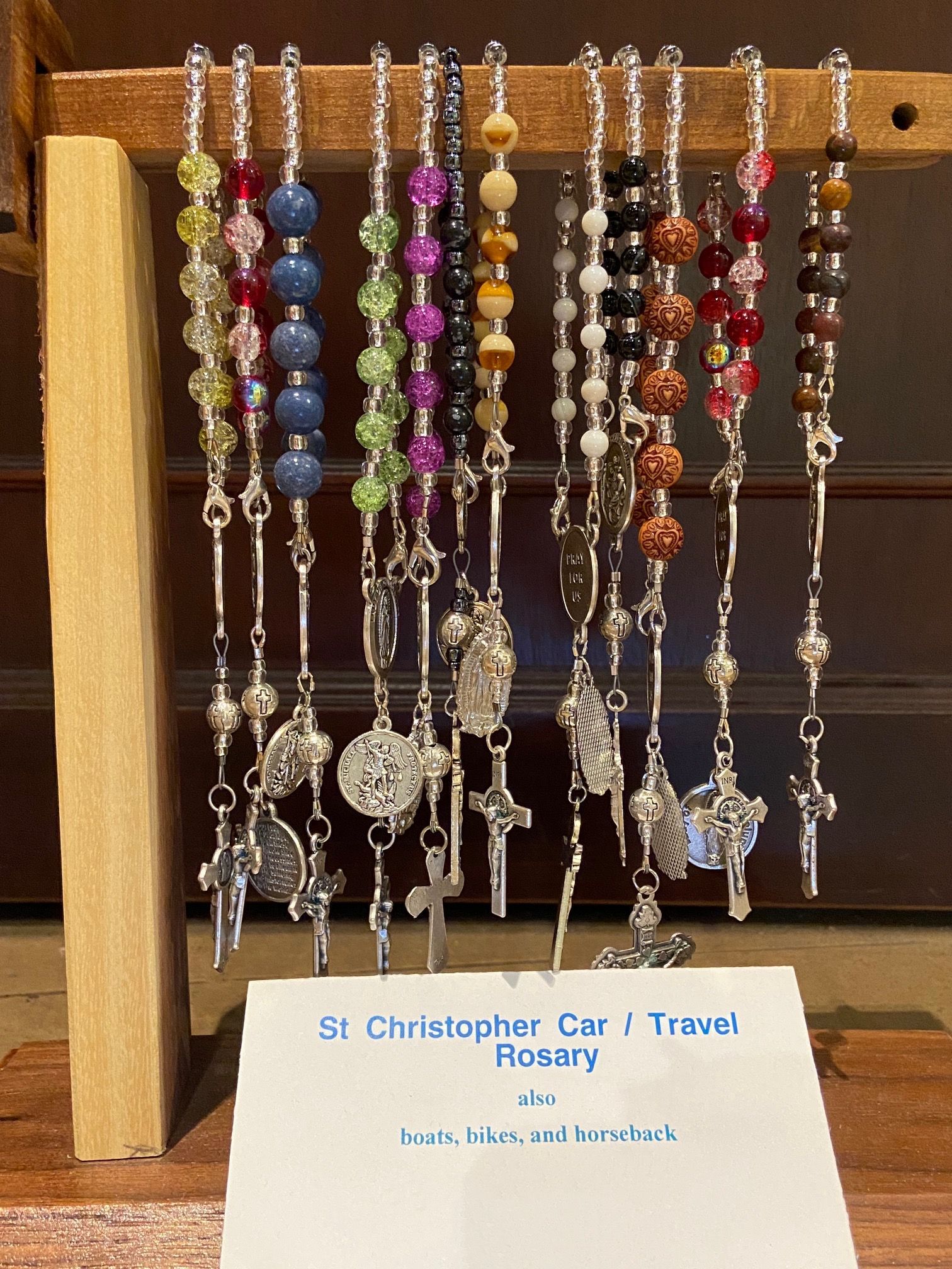 A bunch of rosary beads are displayed on a wooden stand