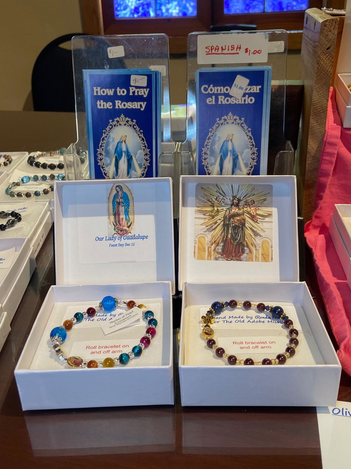 A display of rosary bracelets and a book on how to pray the rosary