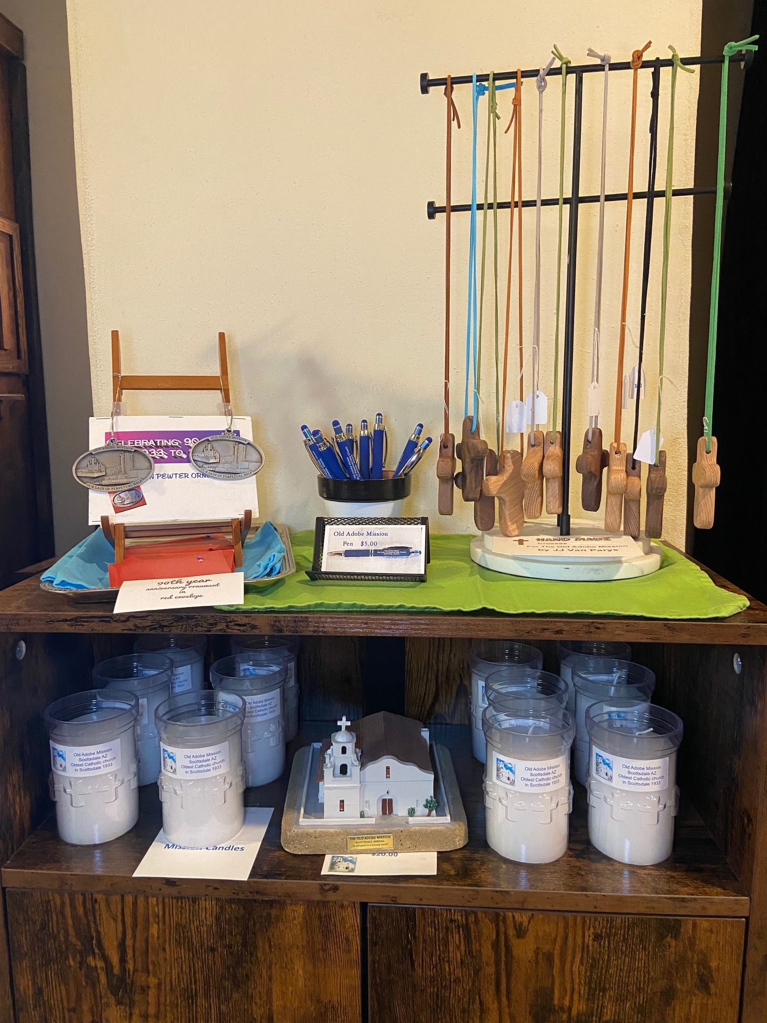 A wooden shelf filled with candles and a model of a church.