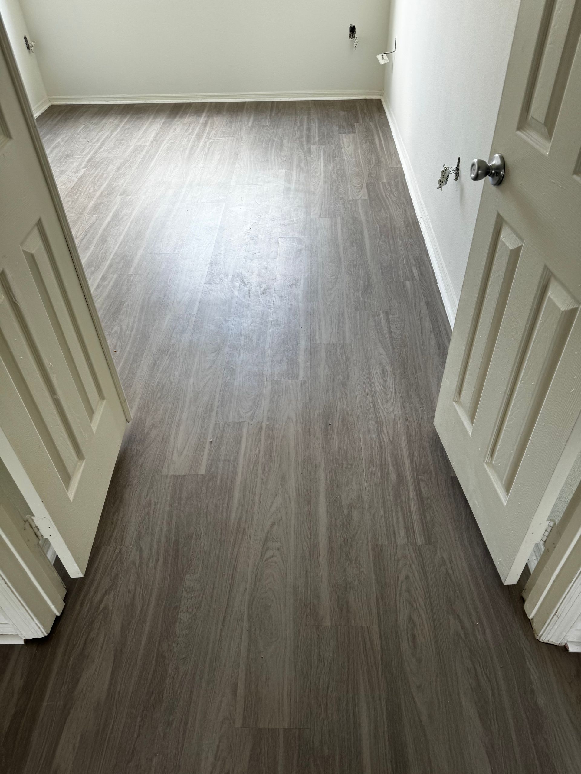 A room with a vinyl flooring and white doors.