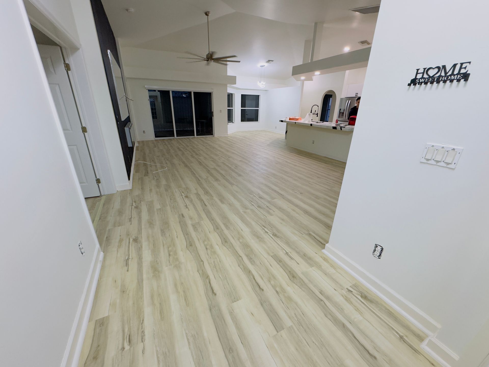 A large room with vinyl floors and a ceiling fan.