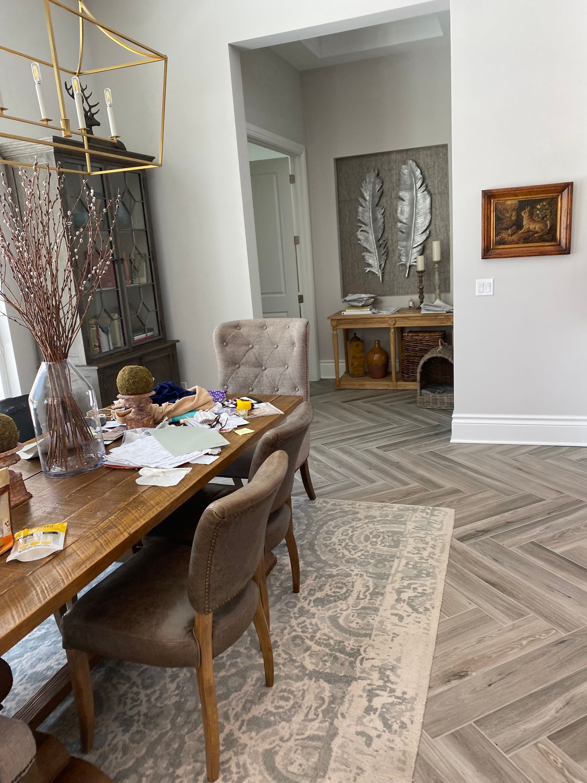 A messy dining room with a wooden table and chairs.