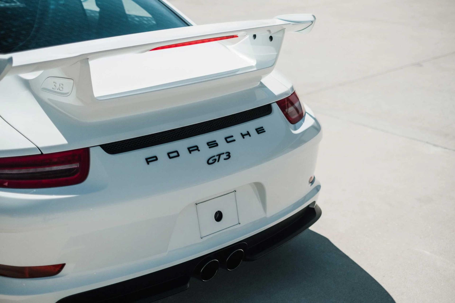 White Porsche GT3 rear view, with spoiler and exhaust pipes.