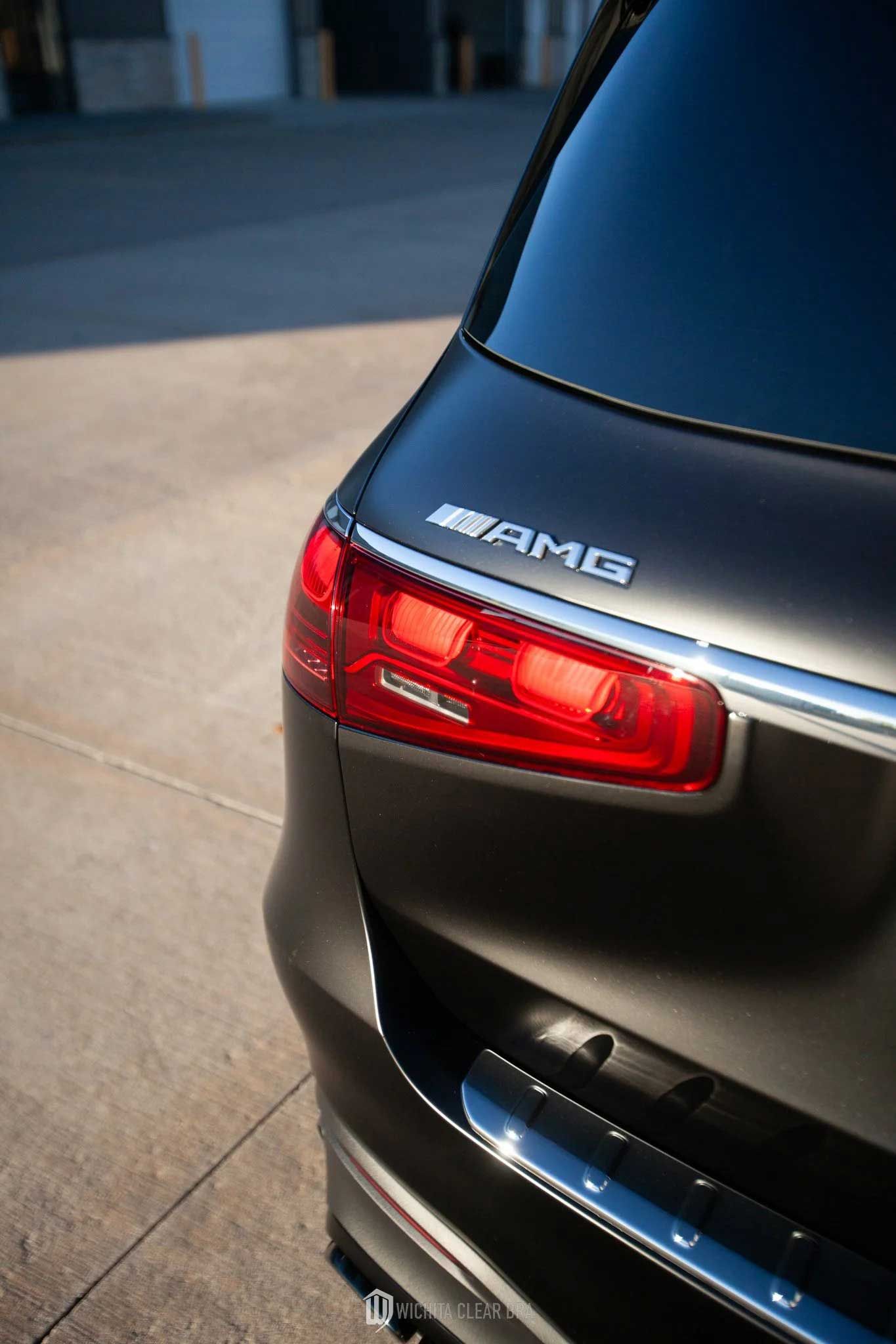 Black Mercedes-AMG SUV rear, with red taillight and chrome trim, parked on a concrete surface.