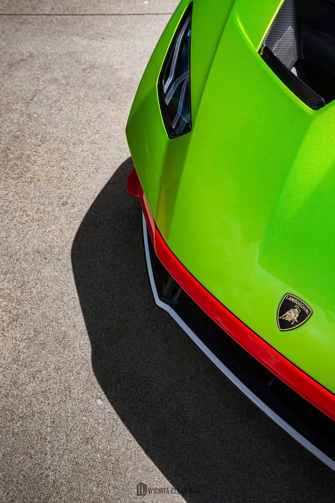 Green Lamborghini car front, red and black accents, concrete ground, Lamborghini logo visible.