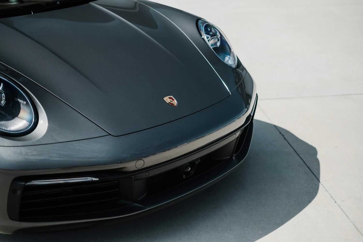 Gray Porsche 911 front with headlights and logo.