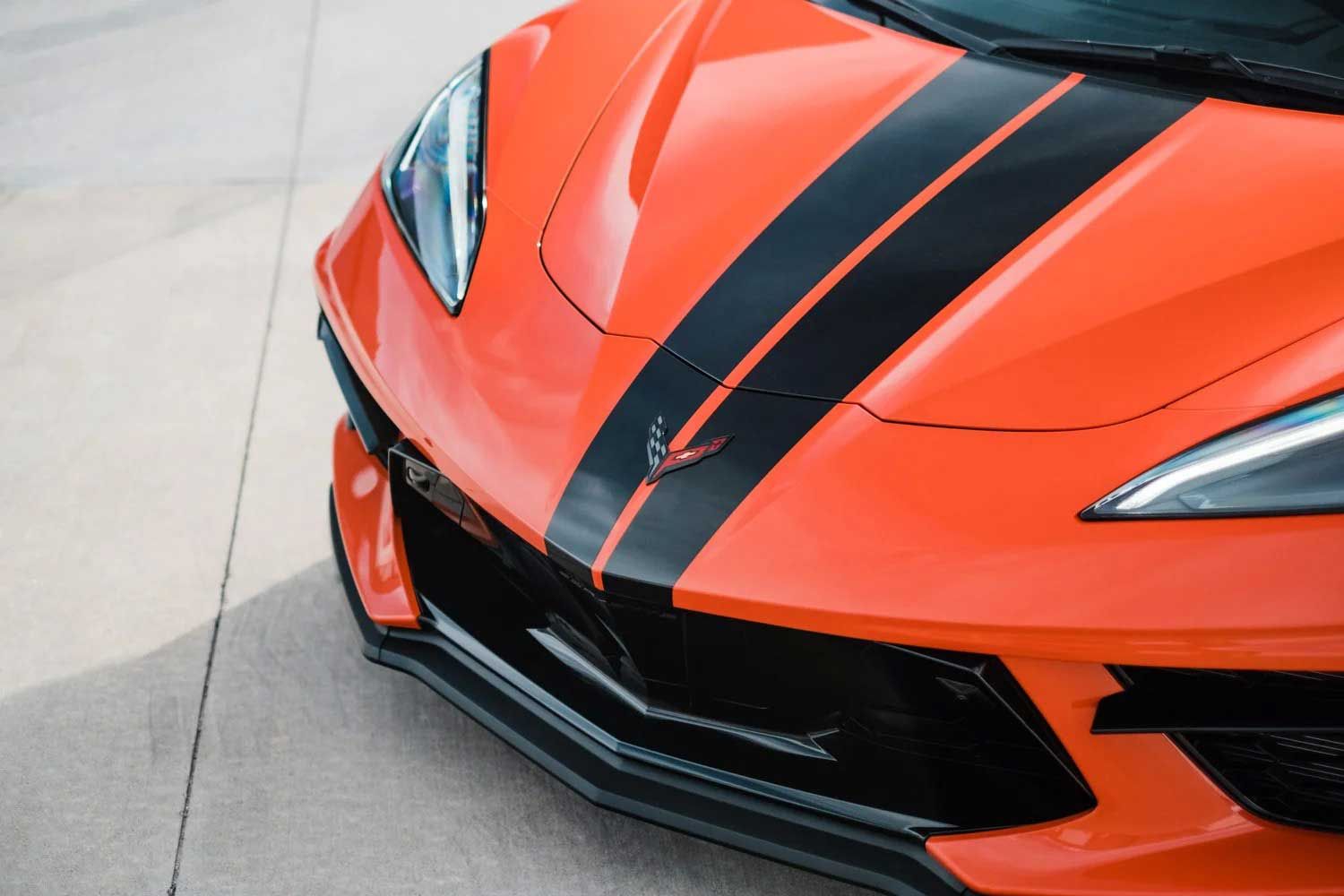 Orange sports car hood with black racing stripes.