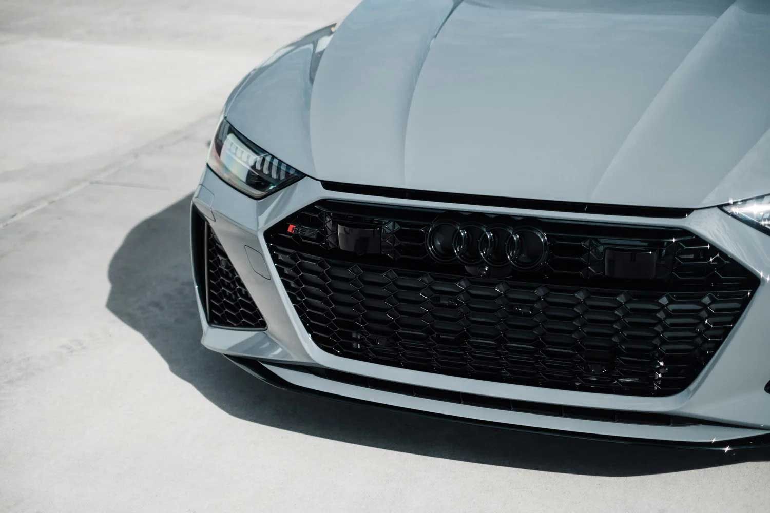 Gray Audi RS 7 front grill, black accents, on a light concrete surface.