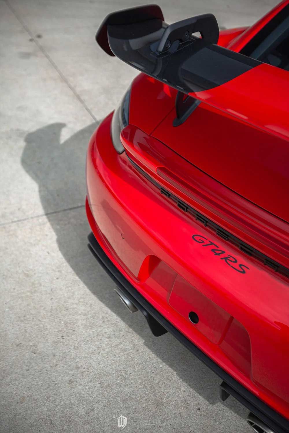 Red Porsche GT2 RS rear detail with spoiler on concrete.