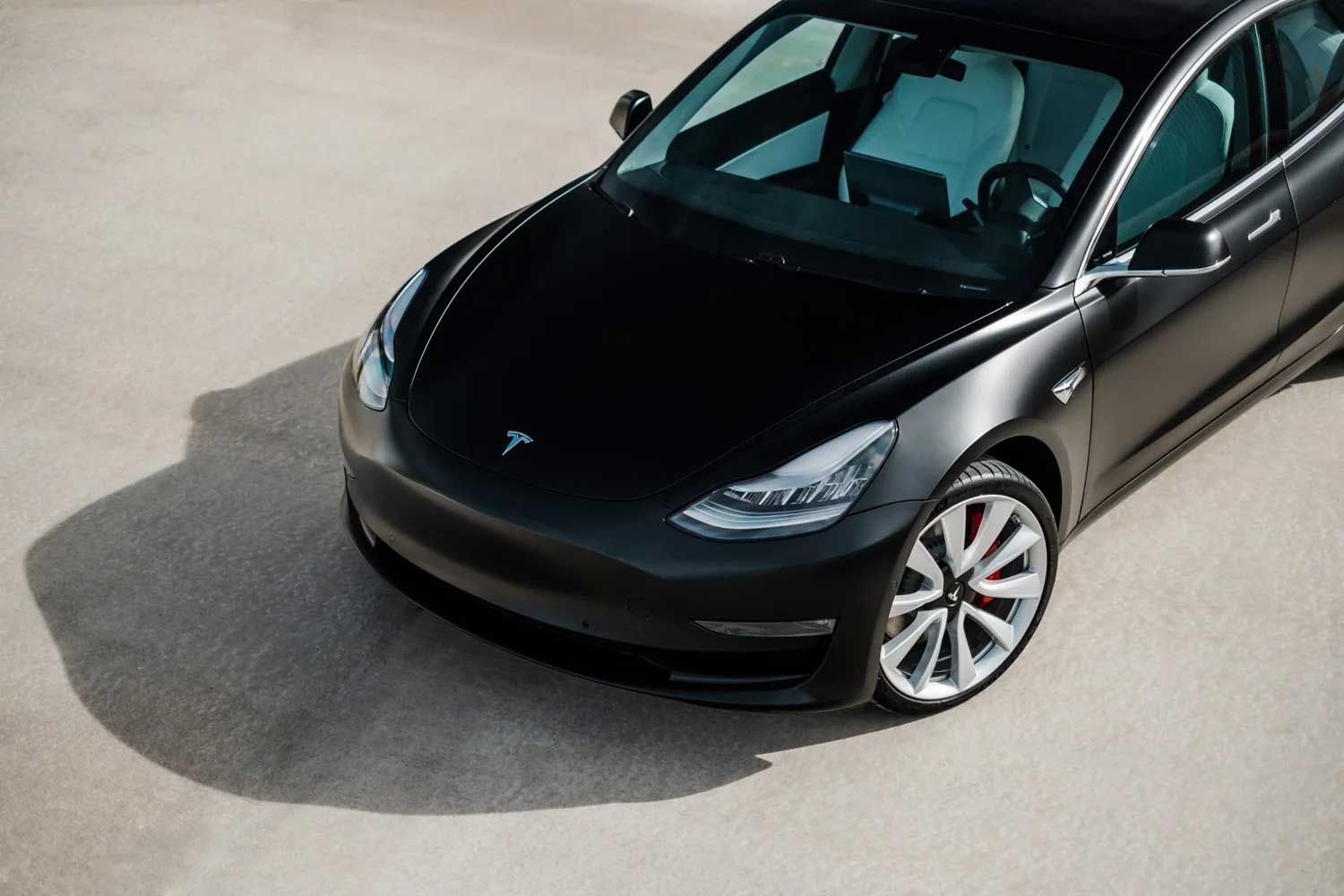 Black Tesla Model 3 car parked on a concrete surface.