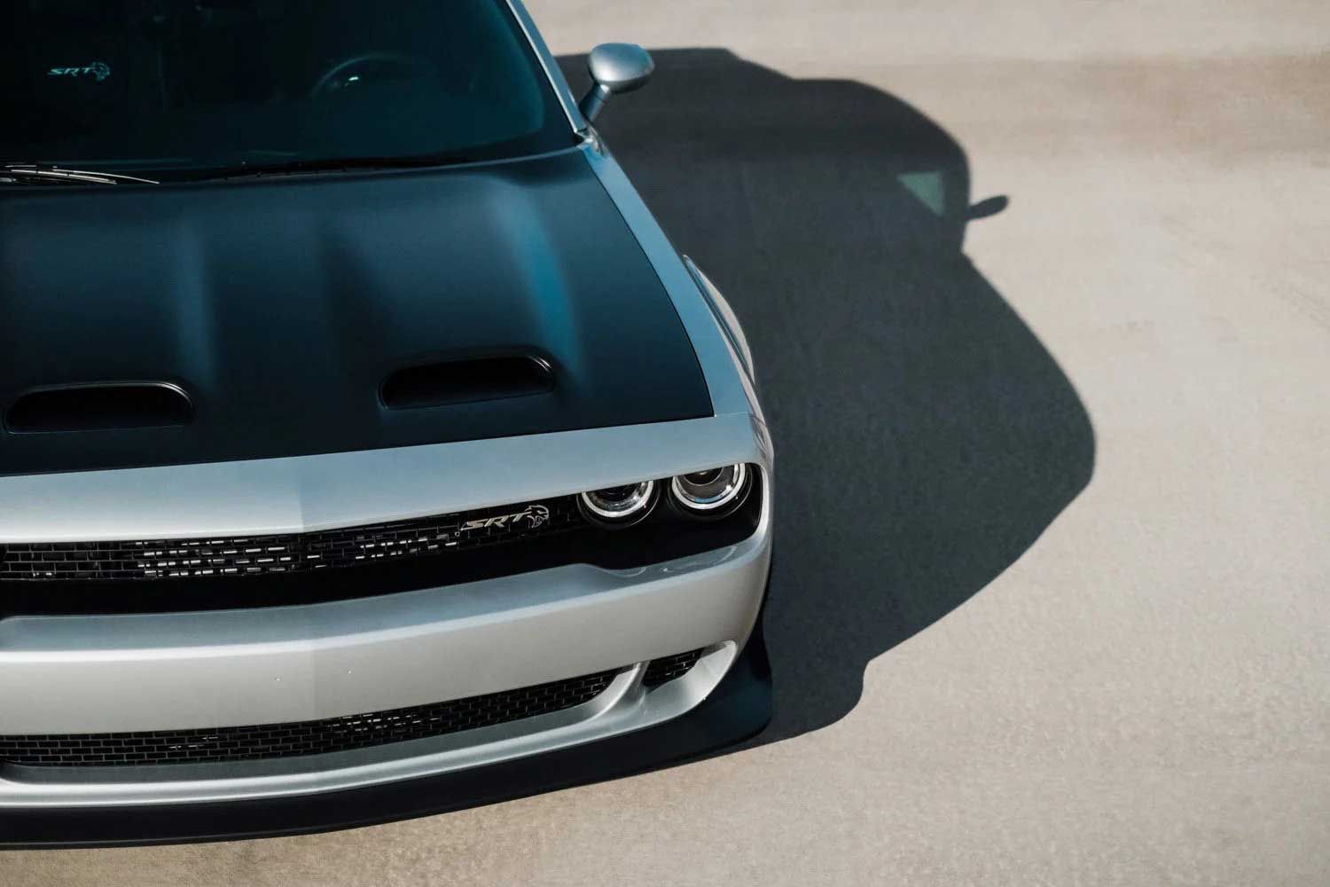Silver and black Dodge Challenger, front view. Hood scoop, black grille, and two headlights.