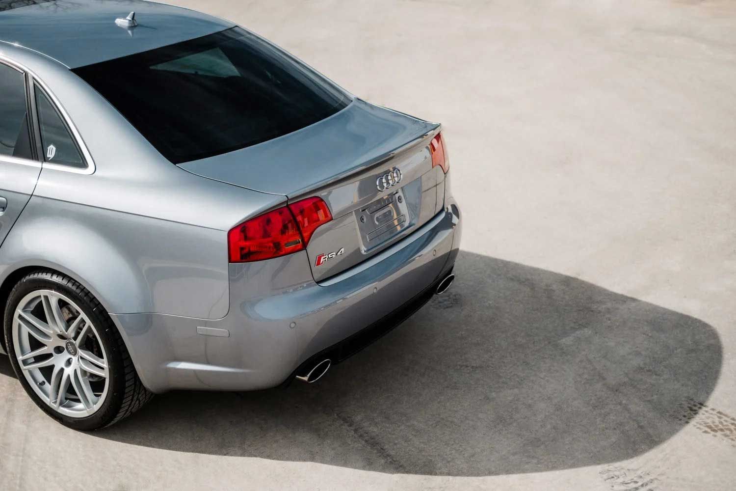 Silver Audi RS4 sedan, rear view, on a light-colored surface, with shadows.
